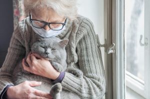 Elderly,Woman,In,Protective,Mask,Holding,A,Cat,Looks,Out